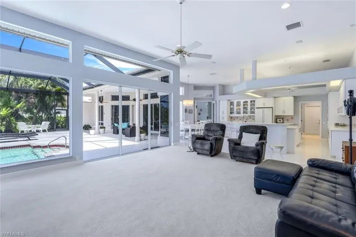 Carpeted living room with a high ceiling, a wealth of natural light, and ceiling fan