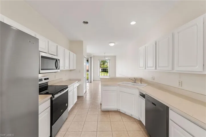 Kitchen featuring sink, appliances with stainless steel finishes, white cabinetry, and light tile patterned flooring