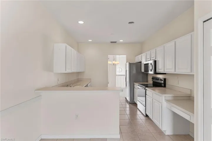 Kitchen featuring kitchen peninsula, appliances with stainless steel finishes, and white cabinets