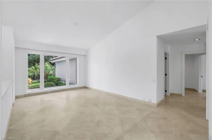 Unfurnished room with baseboards and high vaulted ceiling