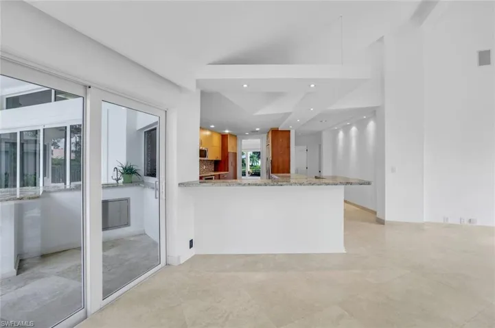 Kitchen with recessed lighting, a peninsula, brown cabinets, and light stone counters