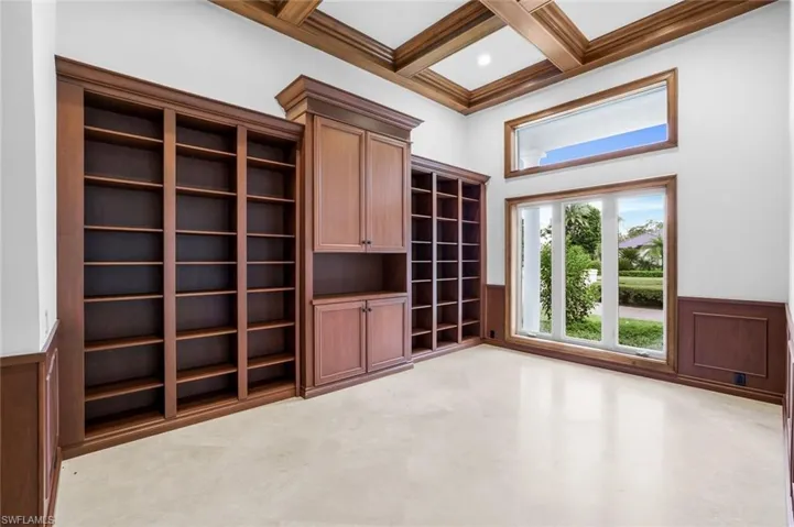 Unfurnished living room with wainscoting, coffered ceiling, beamed ceiling, a decorative wall, and a towering ceiling