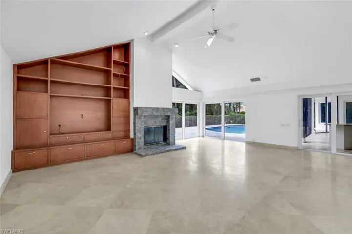 Unfurnished living room with a glass covered fireplace, beamed ceiling, high vaulted ceiling, a ceiling fan, and built in shelves