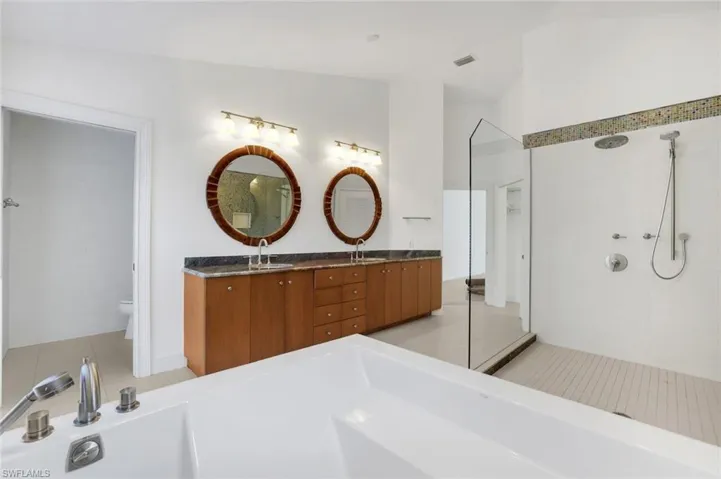 Full bathroom featuring tiled shower, light tile patterned floors, a freestanding bath, and lofted ceiling