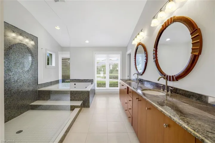 Full bath featuring double vanity, light tile patterned floors, a bath, recessed lighting, and lofted ceiling