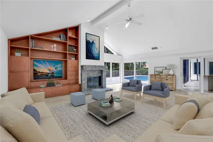 Living room featuring beam ceiling, a glass covered fireplace, high vaulted ceiling, and a ceiling fan Virtually Staged