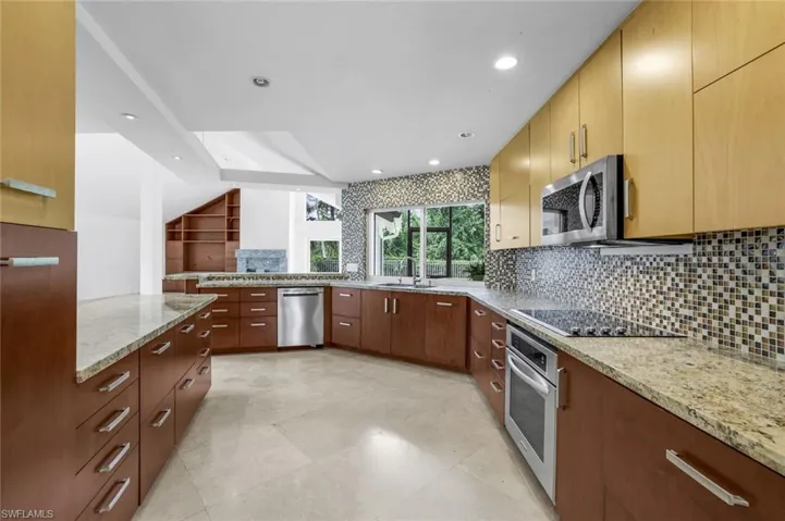Kitchen featuring decorative backsplash, recessed lighting, light stone countertops, stainless steel appliances, and modern cabinets
