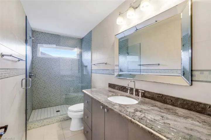 Full bathroom with vanity, a stall shower, tile walls, and light tile patterned flooring
