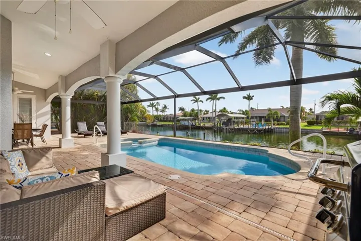 Outdoor pool with a patio area, a sunroom, a water view, glass enclosure, and a residential view