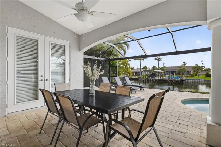 View of patio / terrace featuring an outdoor pool, a sunroom, french doors, a water view, and glass enclosure