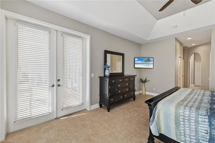 Bedroom with arched walkways, ceiling fan, light tile flooring, lofted ceiling, and recessed lighting