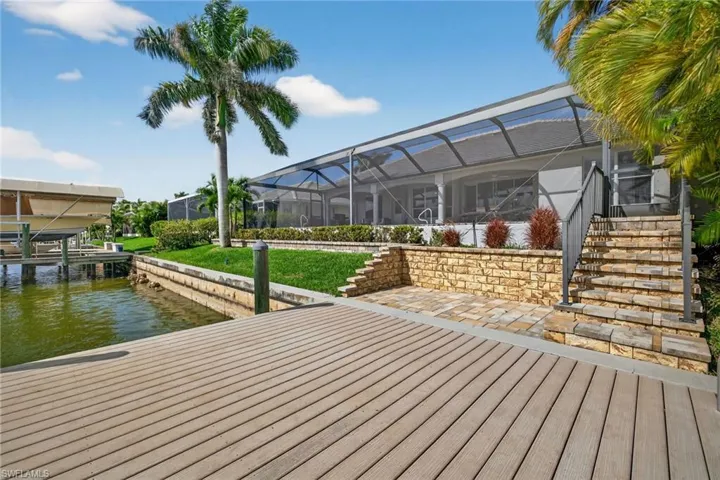 Dock featuring a lanai, a sunroom, a water view, and a yard