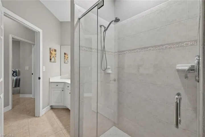 Full bathroom with vanity, a stall shower, and light tile flooring