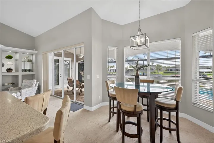 Dining space featuring light tile patterned flooring, vaulted ceiling, and suspended lighting