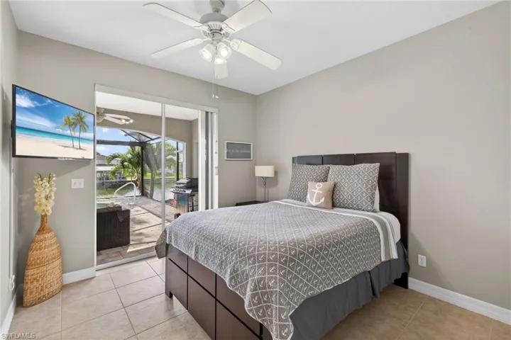 Bedroom with a sunroom, light tile patterned floors, access to exterior, and a ceiling fan