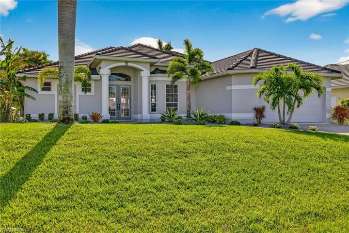 View of front facade featuring french doors, a tile roof, a front lawn, and a garage