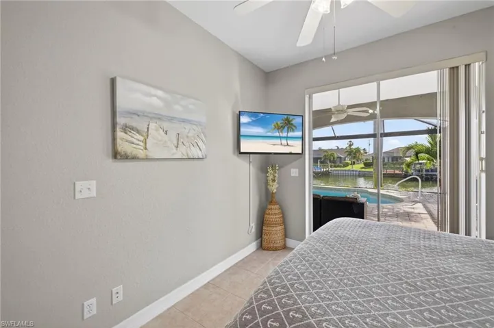 Bedroom featuring a ceiling fan, access to exterior, light tile patterned floors, a sunroom, and a textured wall