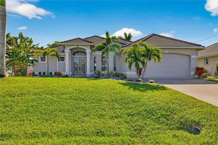 Mediterranean / spanish-style house featuring french doors, a tiled roof, a front lawn, stucco siding, and driveway