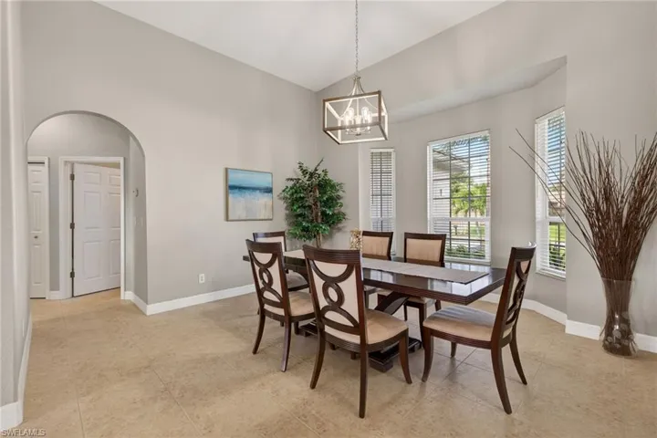 Dining space with arched walkways, vaulted ceiling, and hanging lights