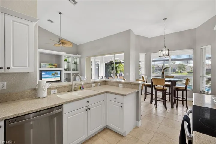 Kitchen with white cabinetry, stainless steel dishwasher, electric range, light stone countertops, and lofted ceiling