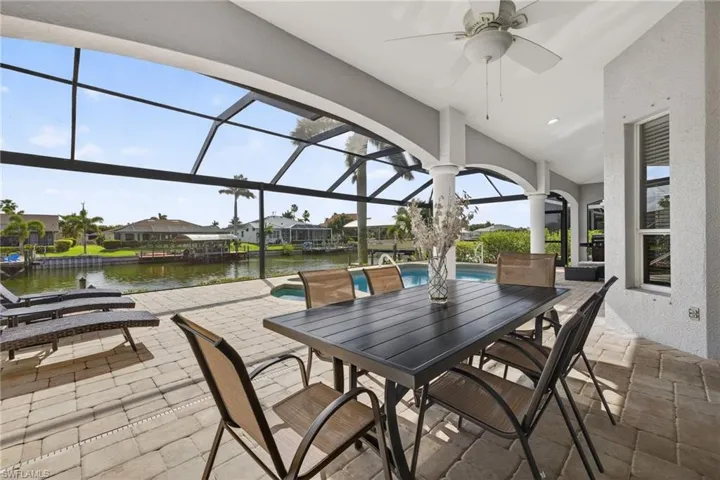 View of patio with a sunroom, a lanai, an outdoor pool, a residential view, and a ceiling fan
