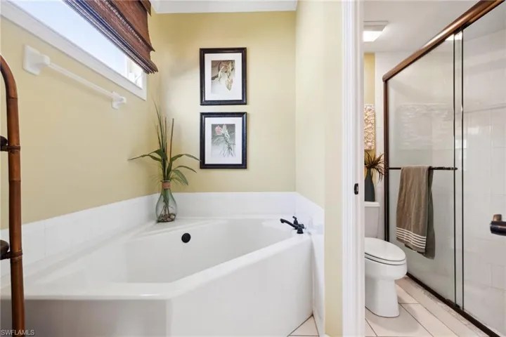 Bathroom featuring a bath, tile patterned flooring, a shower stall, and toilet