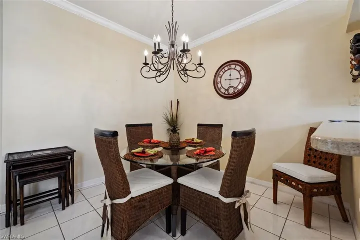 Dining room featuring light tile patterned floors, a notable chandelier, crown molding, and baseboards