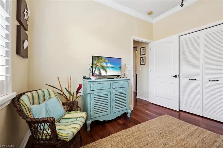 Living area with crown molding, dark wood-style floors, and baseboards