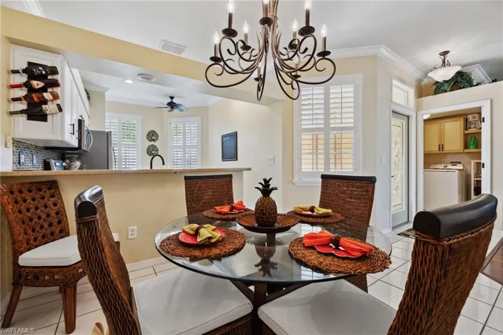 Dining room featuring light tile patterned floors, visible vents, washer / dryer, crown molding, and a notable chandelier