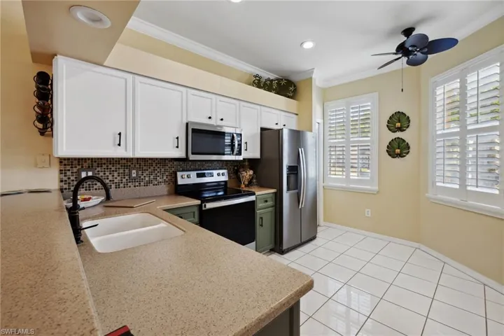 Kitchen featuring a sink, decorative backsplash, white cabinets, appliances with stainless steel finishes, and crown molding