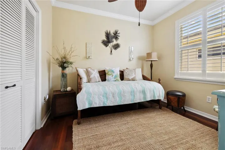 Bedroom with a ceiling fan, crown molding, baseboards, and wood finished floors