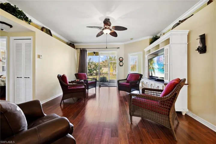 Living room featuring ornamental molding, wood finished floors, baseboards, and ceiling fan