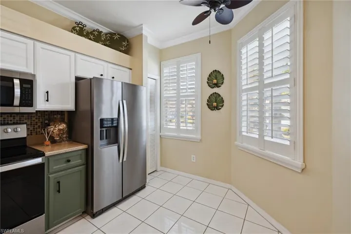 Kitchen with green cabinetry, ceiling fan, ornamental molding, appliances with stainless steel finishes, and backsplash