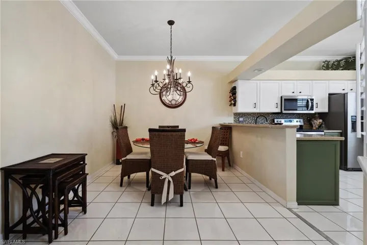 Dining room featuring an inviting chandelier, light tile patterned flooring, crown molding, and baseboards