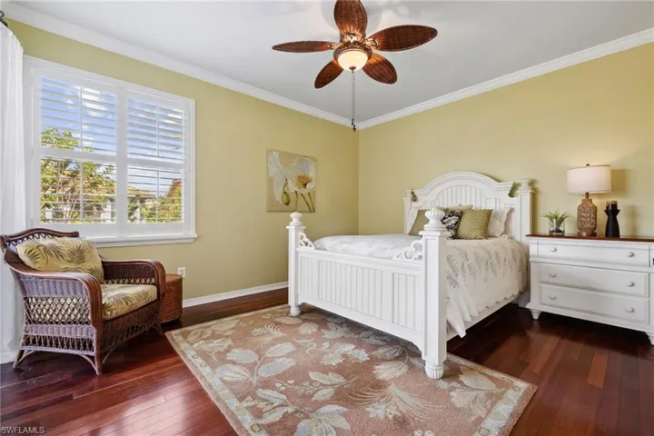 Bedroom with dark wood finished floors, crown molding, a ceiling fan, and baseboards