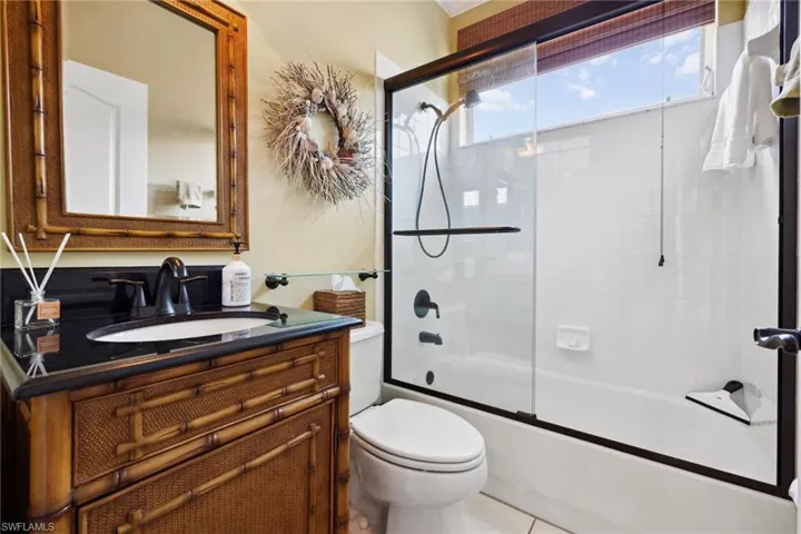 Bathroom with vanity, toilet, and combined bath / shower with glass door