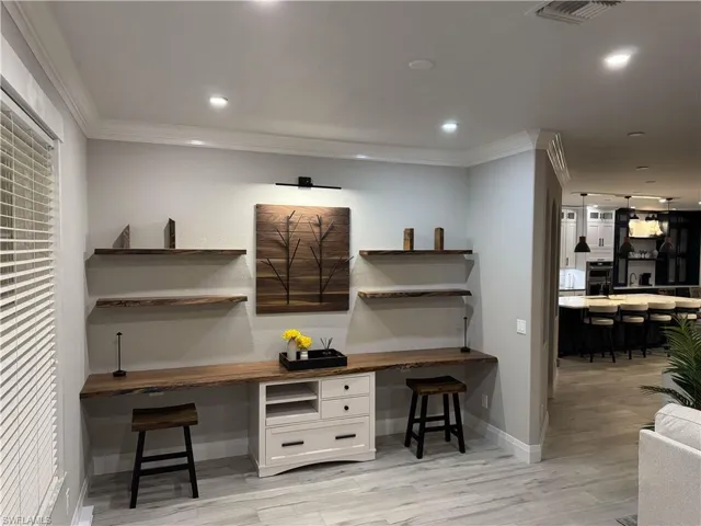 Office area with built in desk, crown molding, light wood-style flooring, and recessed lighting