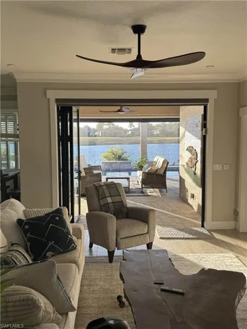 Living area featuring ornamental molding, a ceiling fan, a water view, and light wood-style floors