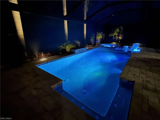 Pool at twilight with a patio area and a pool with connected hot tub