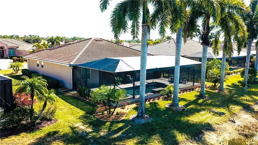Rear view of house with glass enclosure, an outdoor pool, a lawn, and a sunroom