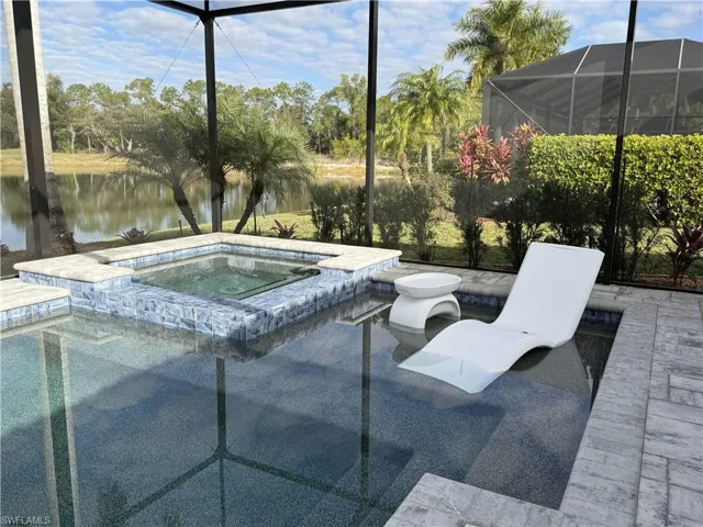 Integrated pool / spa with glass enclosure, a water view, a sunroom, and a patio