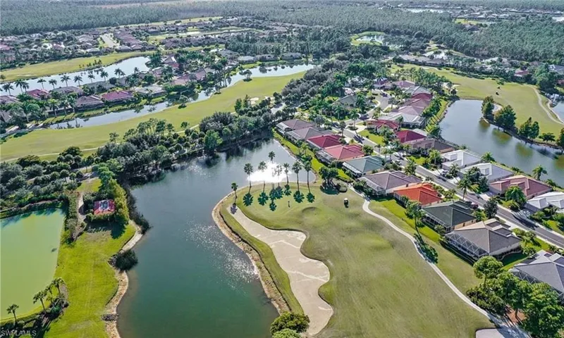 Aerial view of property and surrounding area with nearby suburban area, a golf club, and a large body of water