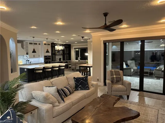 Living room featuring crown molding, light wood-style floors, a ceiling fan, recessed lighting, and a textured ceiling