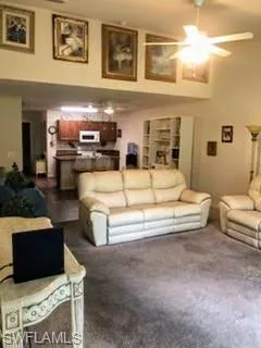 Living room featuring dark colored carpet and ceiling fan