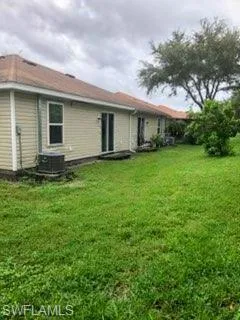 Back of house featuring central air condition unit and a lawn