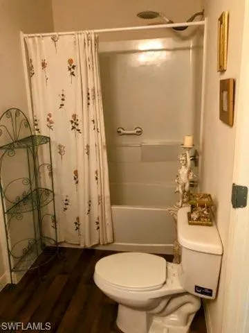 Bathroom with toilet, hardwood / wood-style floors, and shower / tub combo with curtain