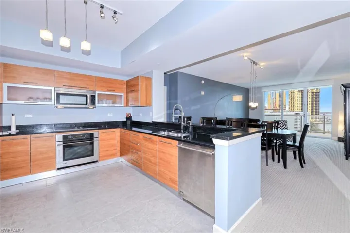 Kitchen with kitchen peninsula, decorative light fixtures, track lighting, appliances with stainless steel finishes, and sink