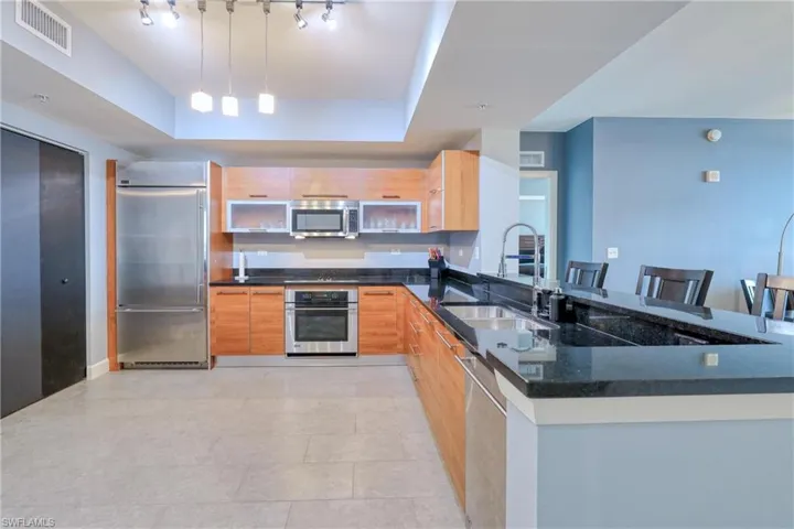 Kitchen featuring appliances with stainless steel finishes, kitchen peninsula, decorative light fixtures, and a breakfast bar area