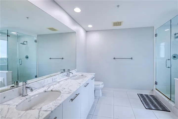 Bathroom featuring toilet, tile patterned flooring, an enclosed shower, and vanity