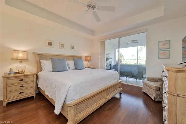 Bedroom with access to exterior, ceiling fan, a raised ceiling, and dark hardwood / wood-style flooring